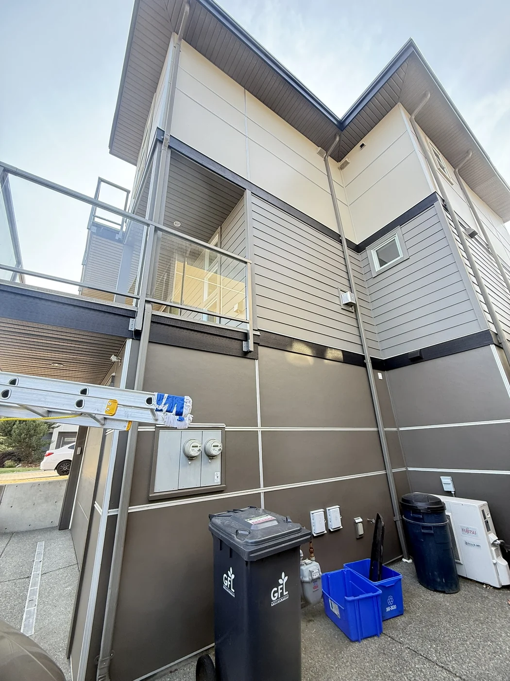 Multi-unit new-build exterior with light panels, dark trim and balconies