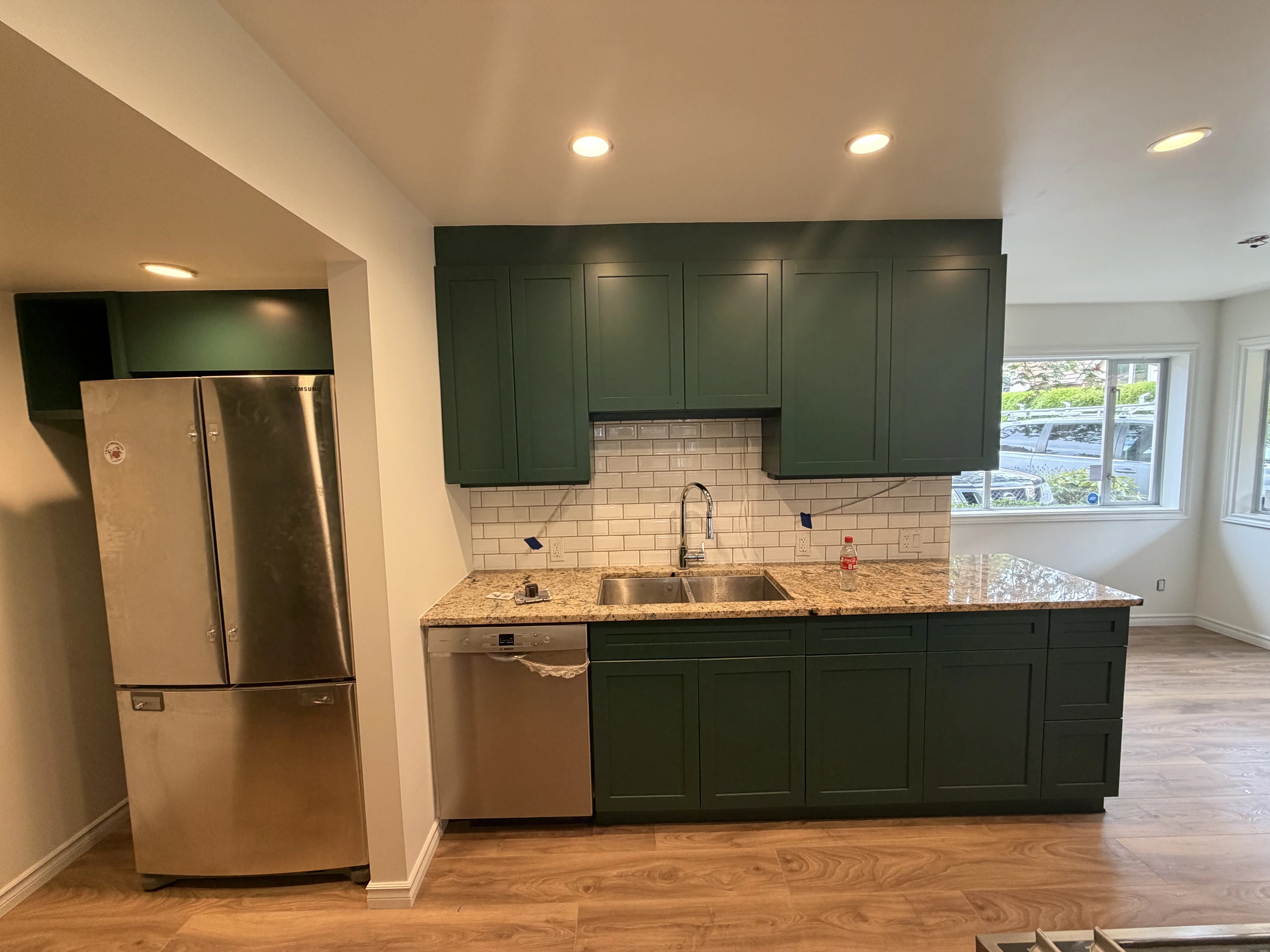 Completed kitchen with deep green upper and lower cabinets, stainless appliance and new flooring